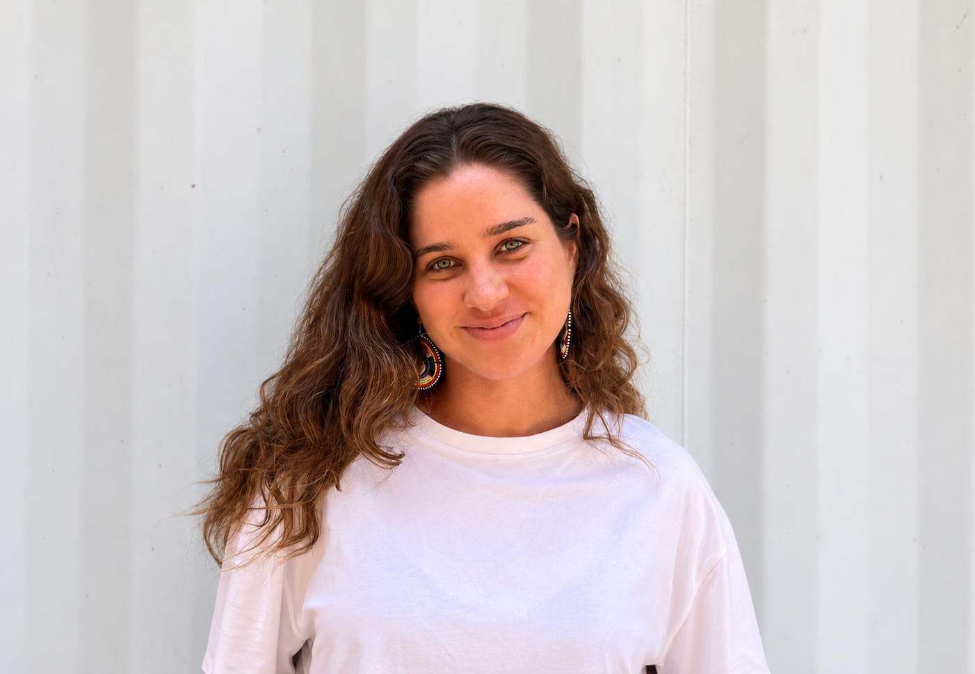 Sobre Nós mulher de branco diante de parede corrugada
